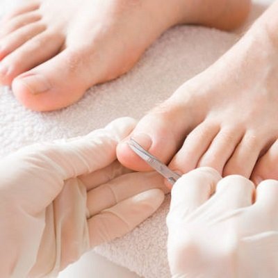 Pedicurist's hands in protective rubber gloves cutting toenails with scissors. Cares about man's feet. Specialist with client in beauty salon. Professional beauty service. Pedicure, manicure concept.